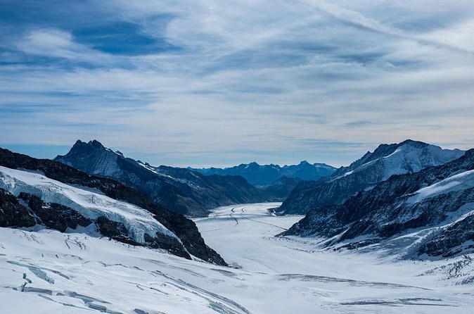 A broad glacier flowing away between dark rock ridges and snow peaks