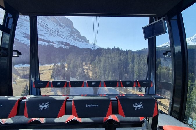 Inside a gondola cabin, the seats facing a huge rock face through the window